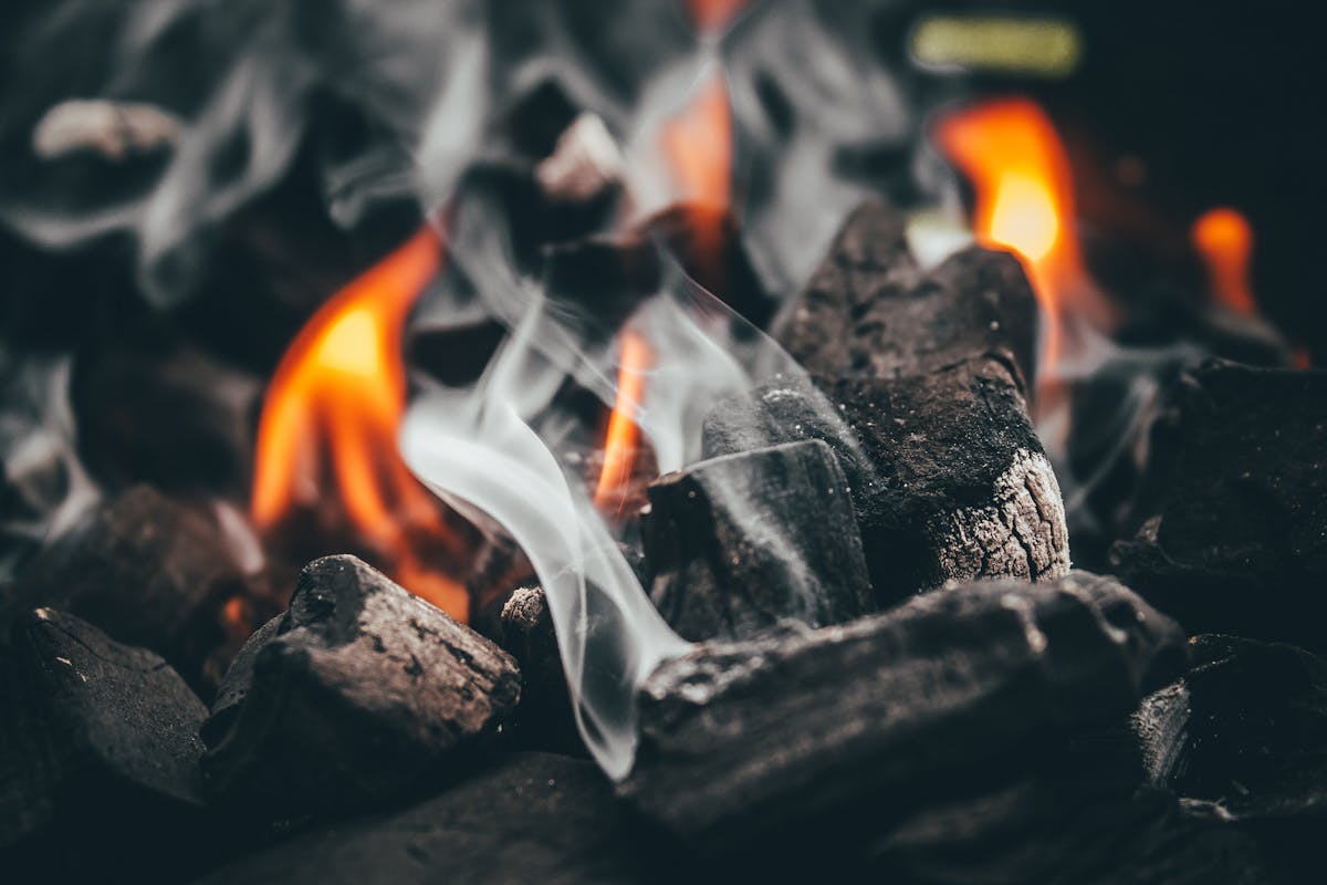 Large binchotan BBQ logs burning with smoke